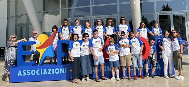 Il team di Uniud per il progetto ALA posa davanti al logo di ExpoAID a RImini